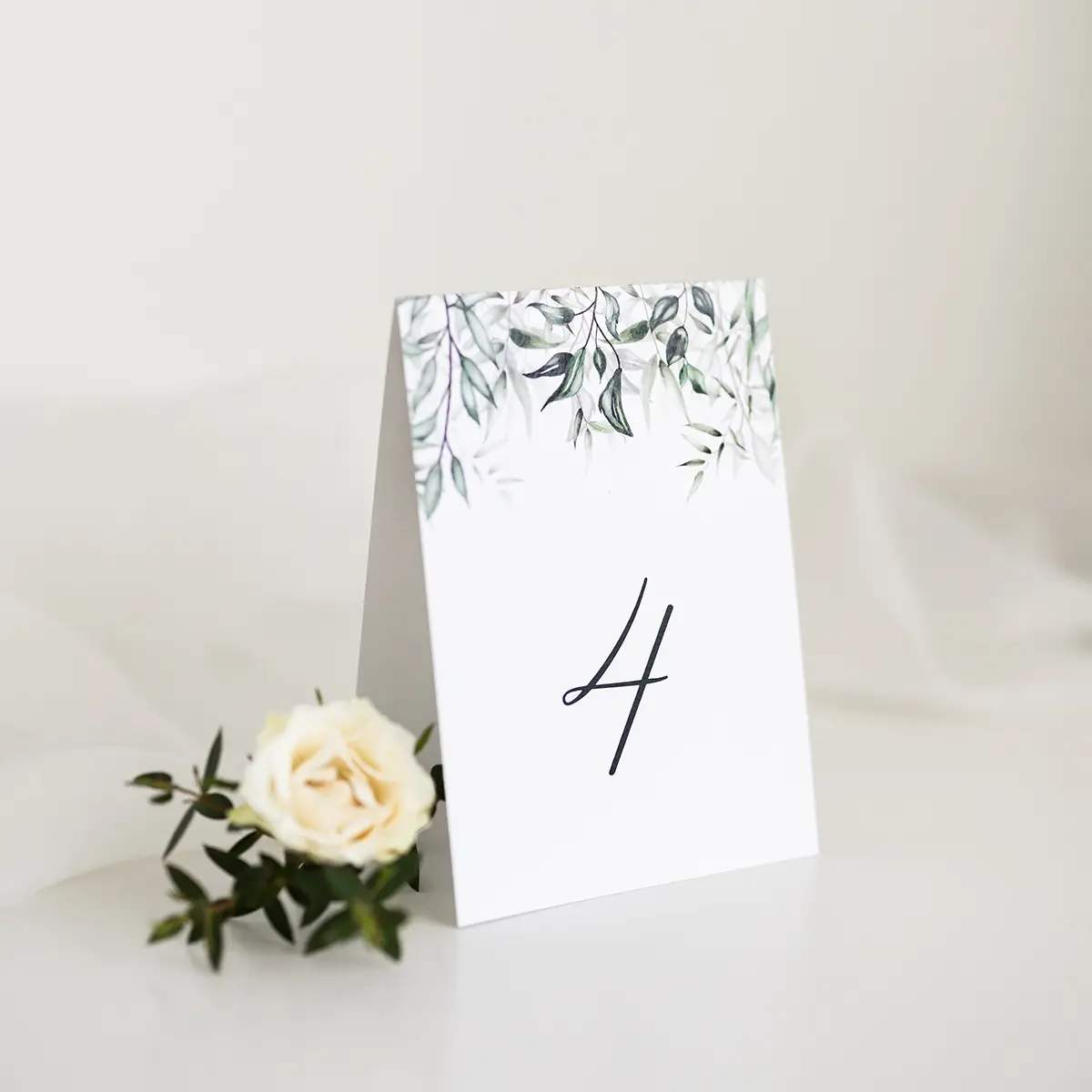 Składany numer stołu w formie daszka, ozdobiony zielonymi liśćmi, doskonały do stylowych przyję