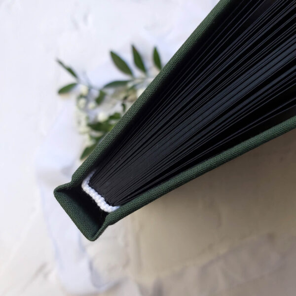 Grzbiet zielonej księgi gości z czarnymi kartami.