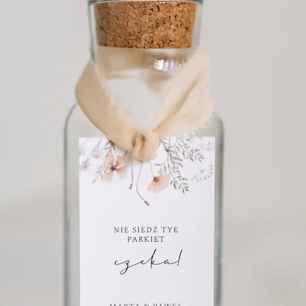 Elegancka zawieszka na alkohol z szarpanej kalki z motywem kwiatowym, przewiązana delikatnym materiałem.