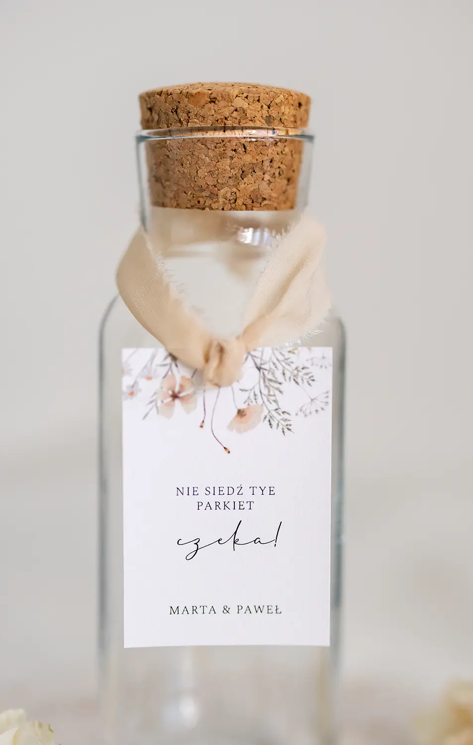 Elegancka zawieszka na alkohol z szarpanej kalki z motywem kwiatowym, przewiązana delikatnym materiałem.