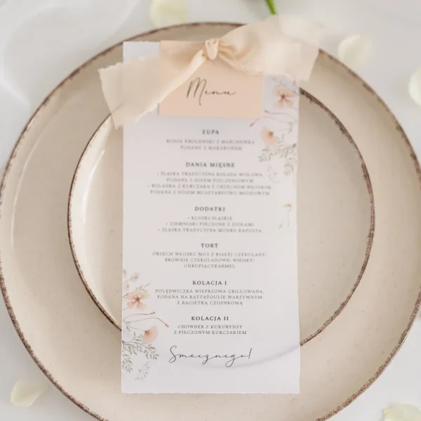 Eleganckie menu weselne na kalce z delikatnym florystycznym wzorem, ozdobione pastelową wstążką.