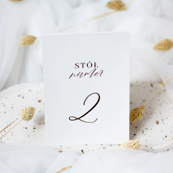 Eleganckie numery stołów z kolekcji Róża, drukowane na gładkim, białym papierze. Czarne cyfry i delikatna czcionka dodają im klasy.