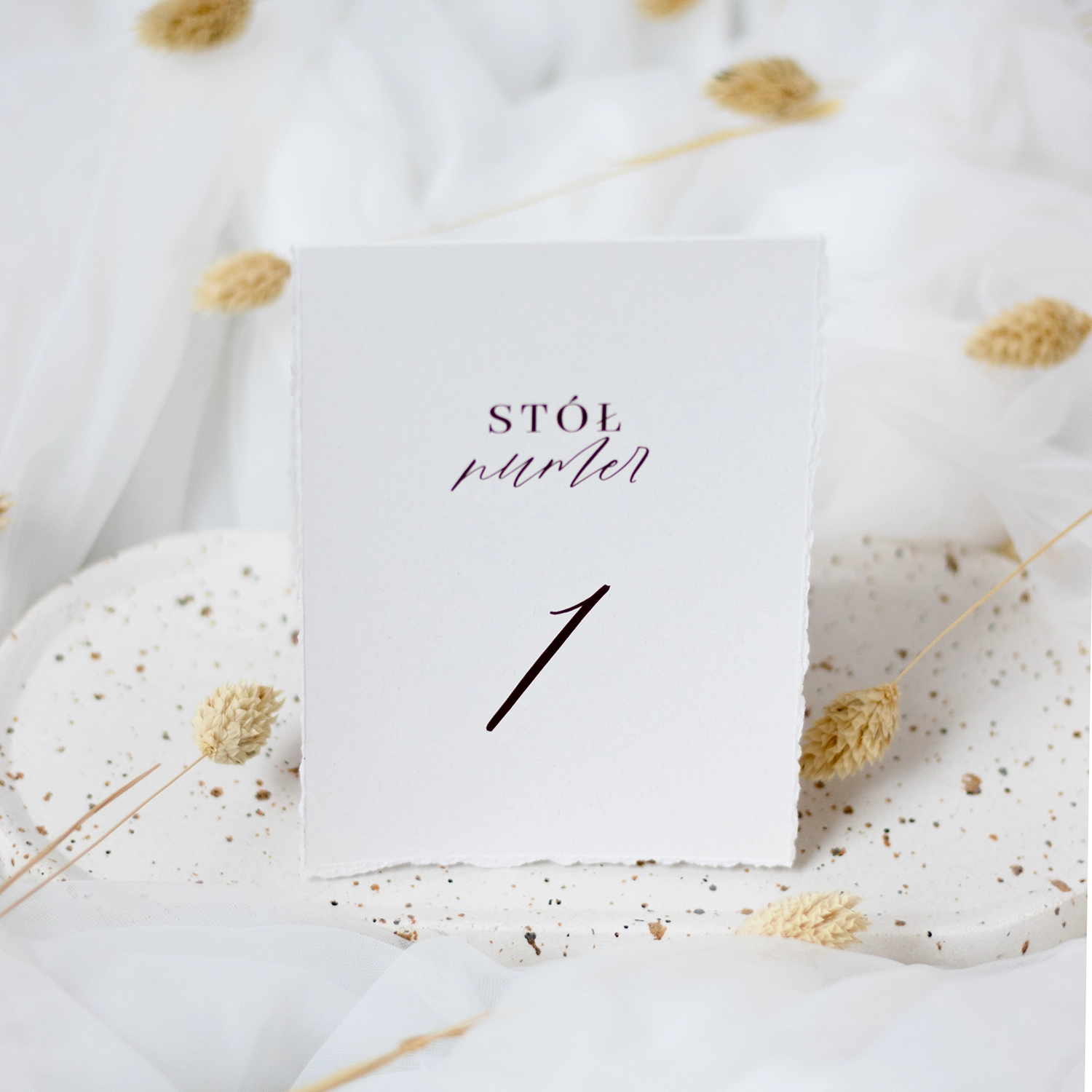 Numery stołów w stylu romantycznym, wykonane na białym, ekologicznym papierze z dekoracyjnymi postrzępionymi brzegami. Minimalistyczna typografia w czerni.