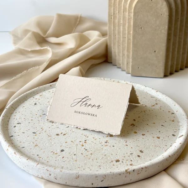 Winietka w kolorze ciasteczkowym, z postrzępionymi brzegami, ustawiona na jasnym talerzu i tle z beżową tkaniną.