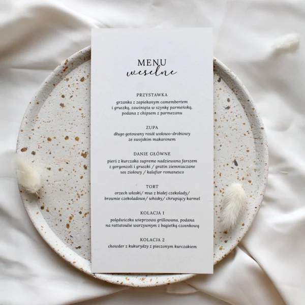 Minimalistyczne menu weselne w odcieniach ecru, prezentowane na jasnym tle z delikatnymi dodatkami dekoracyjnymi.