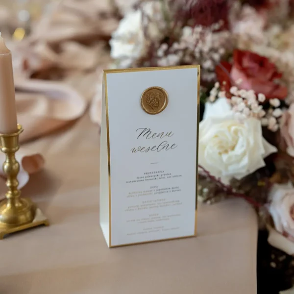 Eleganckie menu weselne z kolekcji Złoty Folder, ozdobione złotym tłoczeniem i lakową pieczęcią.