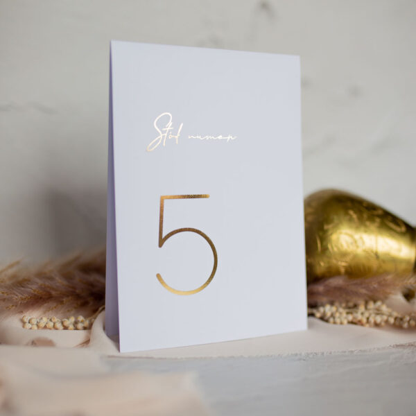 Elegancka numeracja stołów, białe tło ze złotą grafiką.