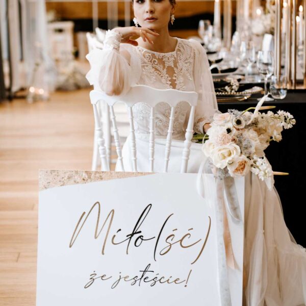 Tablica powitalna ze złotymi zdobieniami.