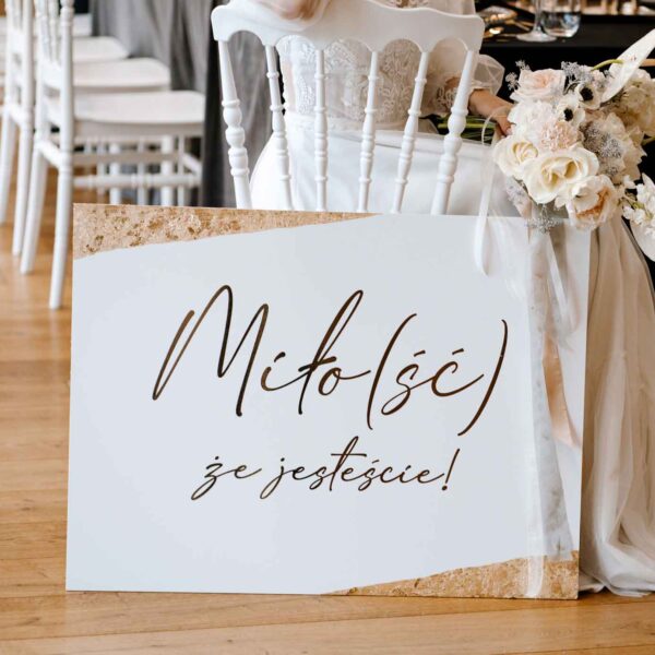 Tablica powitalna ze złotymi zdobieniami.