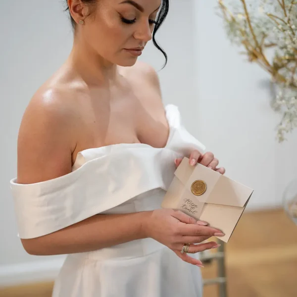 Eleganckie zaproszenie ślubne z kolekcji Złoty Folder w złoto-beżowej kolorystyce z opaską i lakową pieczęcią.