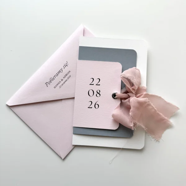 Zaproszenie ślubne w pastelowych odcieniach różu i niebieskiego z wiązaniem z różowej wstążki i elegancką kopertą z nadrukiem.