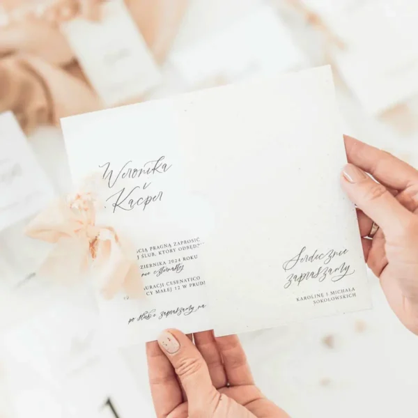 Zaproszenie ślubne z kolekcji Glixia w ozdobnej kieszonce z naturalnego papieru, z subtelnym nadrukiem i ręcznie wiązaną wstążką.