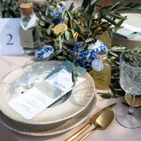 Stylowe nakrycie stołu weselnego z kartą menu i butelką limoncello.