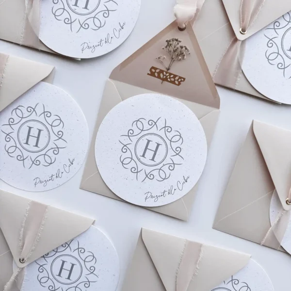 Okrągły bon podarunkowy z logo w eleganckiej kopercie z wstążką, idealny na prezent dla klientów.