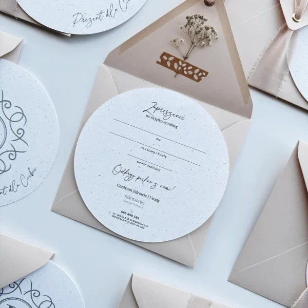 Okrągły voucher podarunkowy z personalizowanym nadrukiem w stylowej, ozdobnej kopercie z gipsówką.