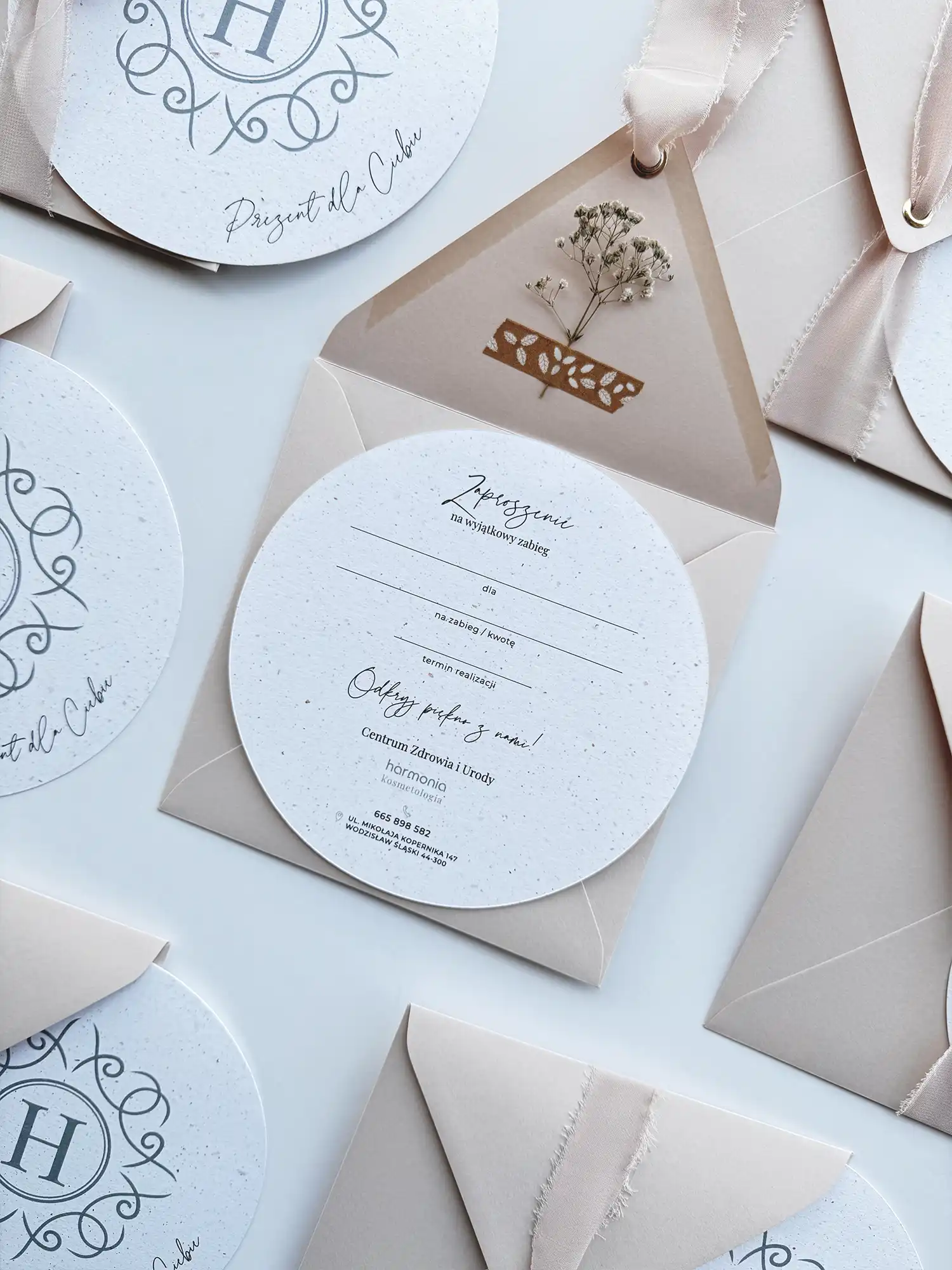 Okrągły voucher podarunkowy z personalizowanym nadrukiem w stylowej, ozdobnej kopercie z gipsówką.