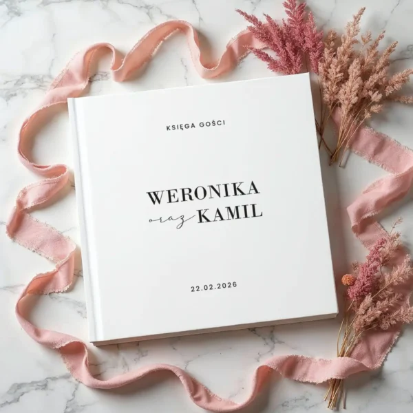 Minimalistyczna księga gości weselnych ozdobiona różową wstążką i suszonymi kwiatami.