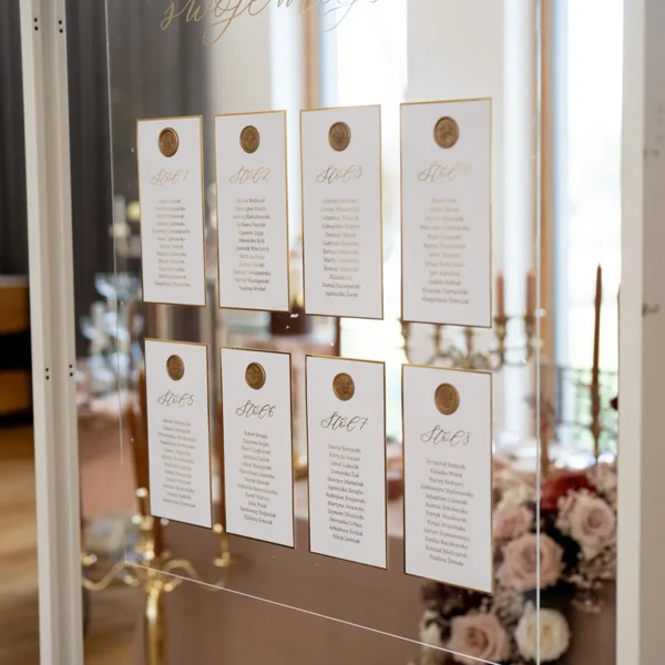 Plan stołów weselnych z kolekcji Złoty Folder, ozdobiony złotymi pieczęciami lakowymi i elegancką czcionką.
