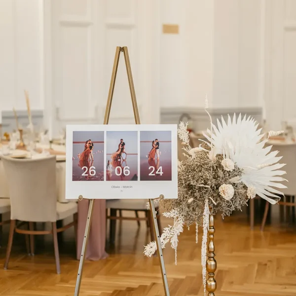 Tablica powitalna na wesele ze zdjęciami stojąca na sali weselnej na sztaludze