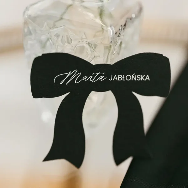 Winietka w kształcie kokardki w czarnym kolorze. Stylowy akcent na eleganckie przyjęcia weselne i uroczystości.