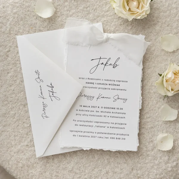 Minimalistyczne białe zaproszenie komunijne z subtelną kaligrafią i elegancką wstążką.