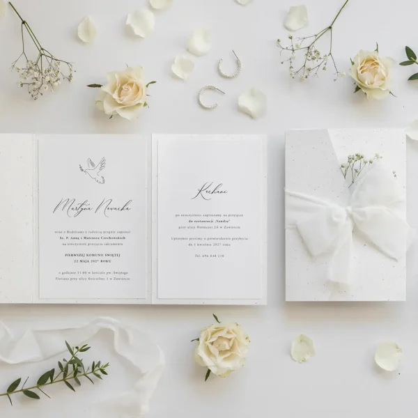 Rozłożone zaproszenie komunijne w folderowej oprawie z gipsówką, pokazujące wnętrze z tekstem zaproszenia.