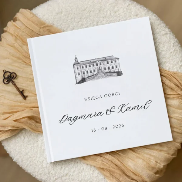 Księga gości z czarno-białym rysunkiem Zamku Chałupki i datą ślubu, umieszczona na jasnej tkaninie