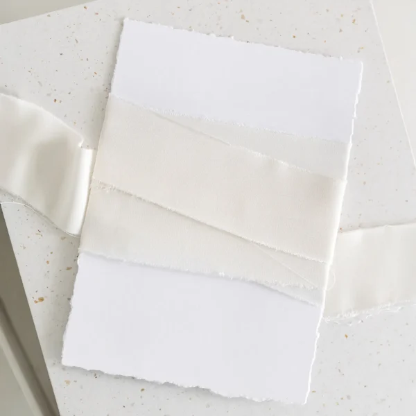 Wstążka satynowa w kolorze waniliowym na tle białego papieru.