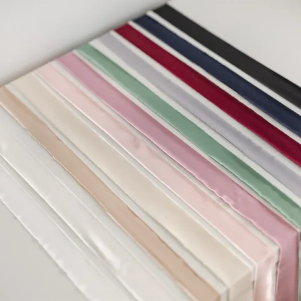 Zestaw kolorowych wstążek satynowych ułożonych w rzędzie na jasnym tle.