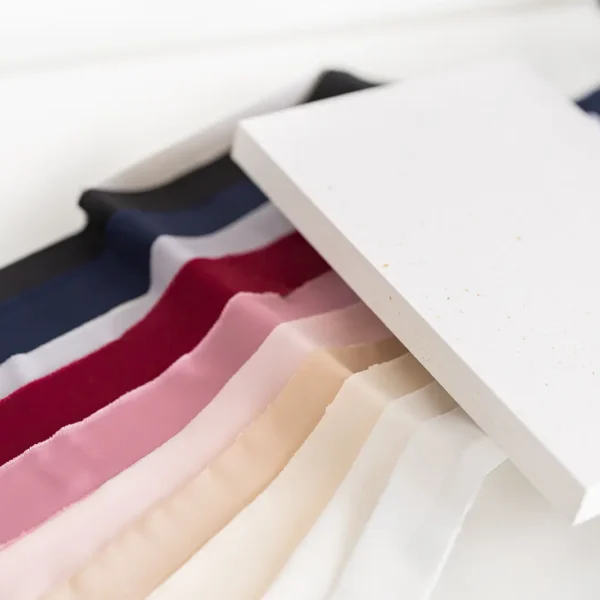 Wzornik kolorów wstążek satynowych ułożonych obok siebie na jasnym tle.