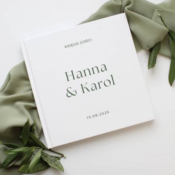 księga gości Jungle w białej oprawie z zielonym napisem, na tle zielonej tkaniny i liści.