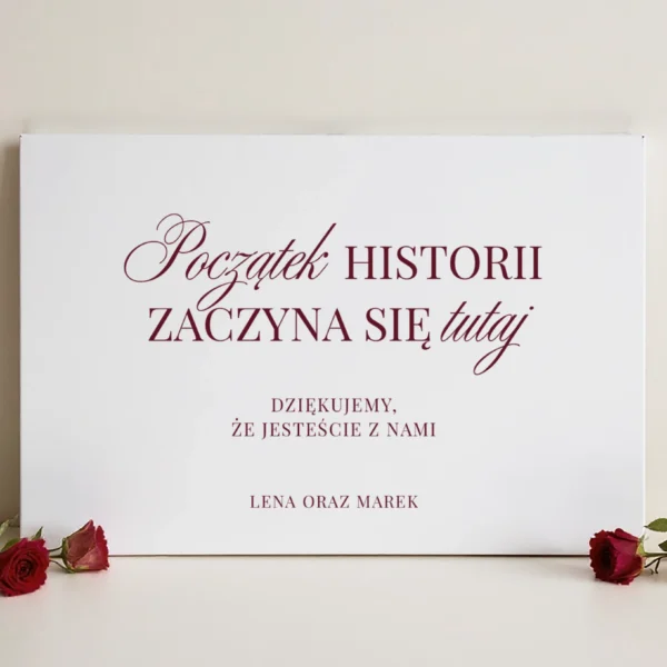tablica powitalna burgundowa z napisem „Początek historii zaczyna się tutaj” w otoczeniu czerwonych róż