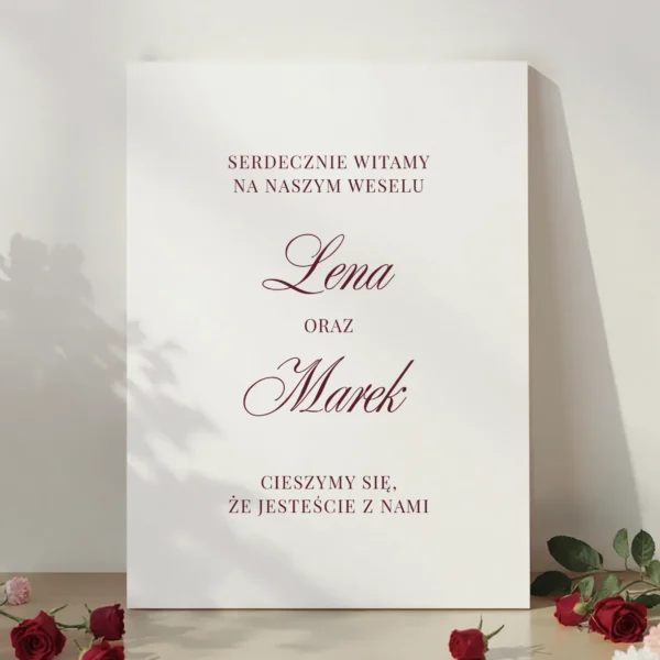 tablica powitalna burgundowa z napisem „Serdecznie witamy na naszym weselu” z dekoracją z czerwonych róż