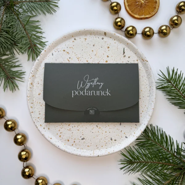 zielony voucher świąteczny z napisem wyjątkowy podarunek ułożony na talerzu z dekoracjami świątecznymi