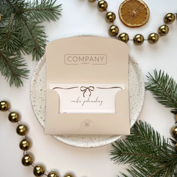 otwarty beżowy voucher świąteczny z kartą podarunkową i kokardką na tle świątecznych dekoracji