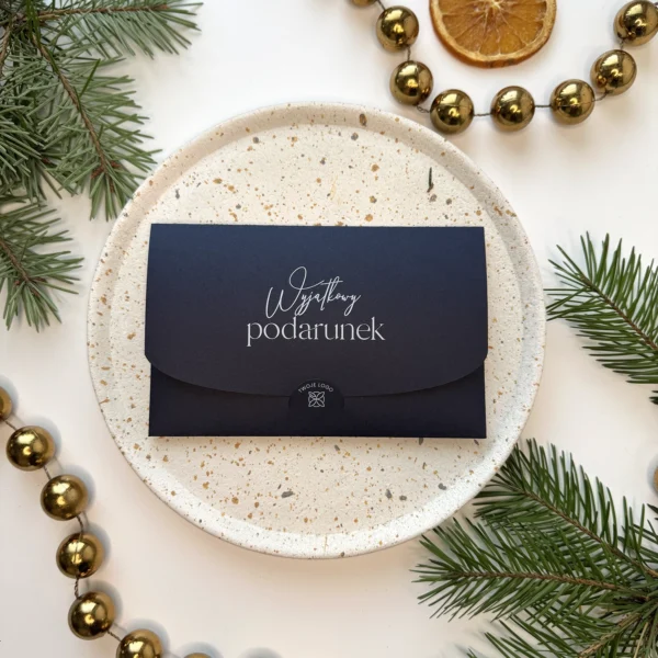 granatowy voucher świąteczny z napisem wyjątkowy podarunek na białym talerzu i tle gałązek świerku