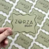 Artystyczne wizytówki w kształcie fal z logo Zorza Studio, wykonane na papierze w odcieniu oliwkowej zieleni.