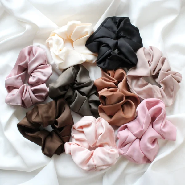 jedwabiste gumki scrunchie ułożone na tkaninie jako propozycja podziękowań na wieczór panieński