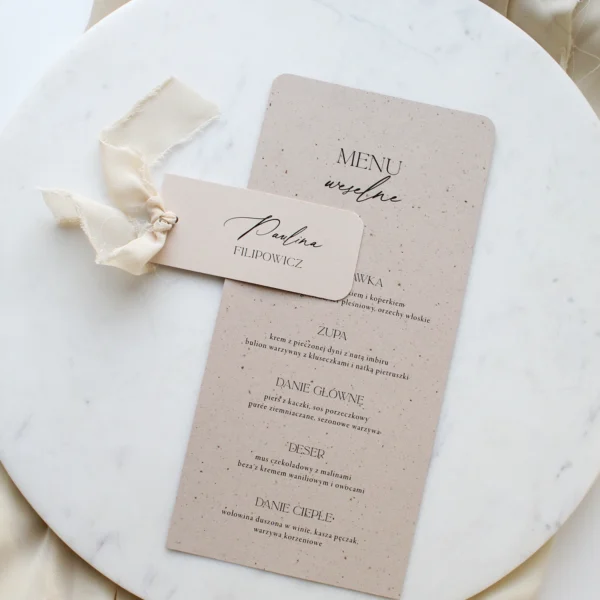 leżące menu weselne na papierze z delikatnymi drobinkami w beżowym odcieniu