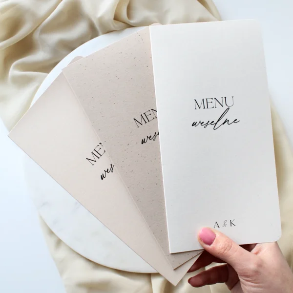 zestaw otwieranych menu weselnych w trzech kolorach trzymanych w dłoni