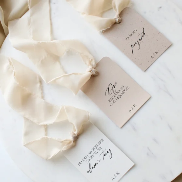 Zawieszki na alkohol z kolekcji kremowej, delikatne papiery i jasna wstążka szyfonowa