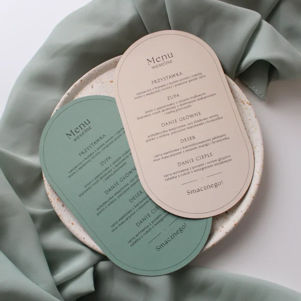 dwa menu weselne Eukaliptus w odcieniach beżu i matcha w kształcie łuku, ułożone na jasnym talerzu