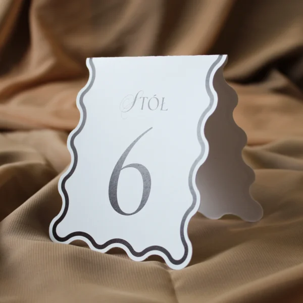 stojący numer stołu z bordowym nadrukiem, widoczny z boku na czerwonym tle