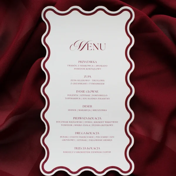 Menu weselne z bordową ramką i falowanymi krawędziami, na tle bordowego materiału
