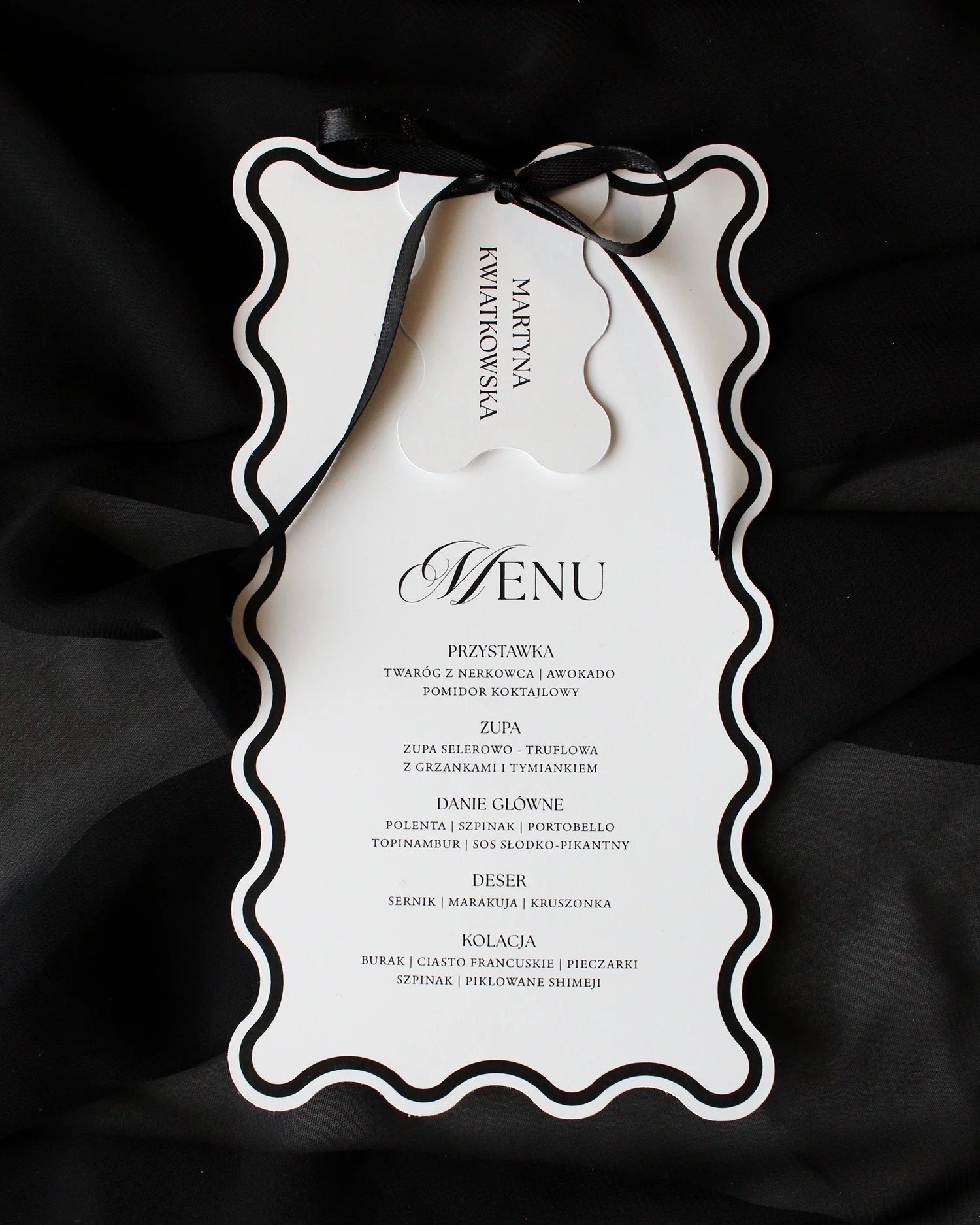 Zestaw Modern Wave z czarnym menu i dopasowaną winietką, przewiązany czarną wstążką.