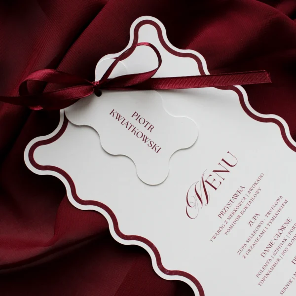 Menu weselne z bordową kokardką i dopasowaną winietką, oba elementy z falowanym brzegiem.