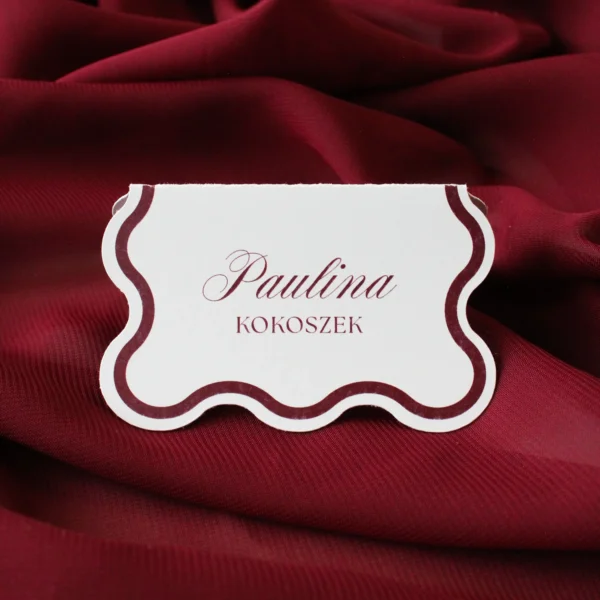 Winietka w kolorze burgundowym z ozdobnym brzegiem, ustawiona na tle bordowego materiału