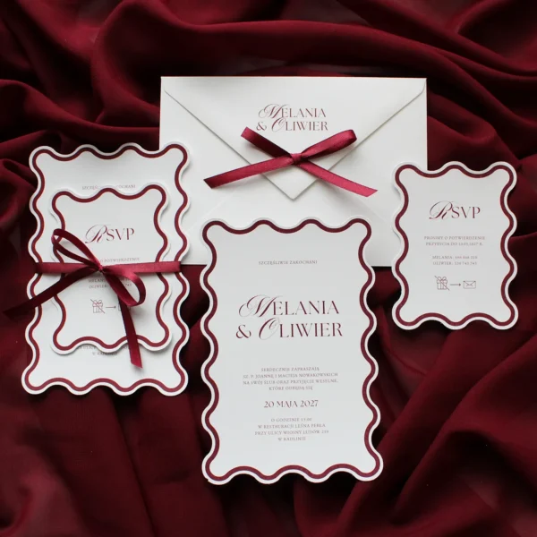 zaproszenie ślubne z falowanymi brzegami i elegancką typografią na tle bordowego materiału