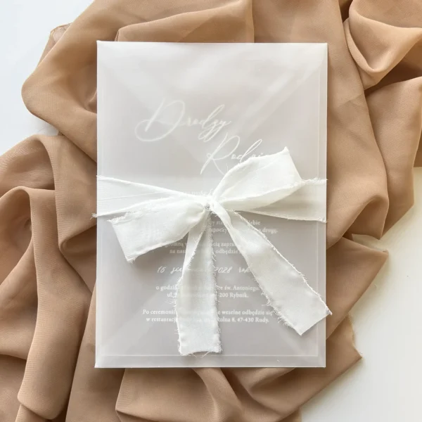 zaproszenie dla rodziców w kopercie z kalki przewiązane białą kokardą z szyfonu