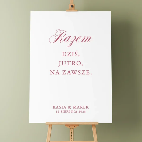 Tablica powitalna z kolekcji Forest na drewnianej sztaludze, z napisem „Razem dziś, jutro, na zawsze” w ciemnoróżowym kolorze, na tle oliwkowozielonej ściany.